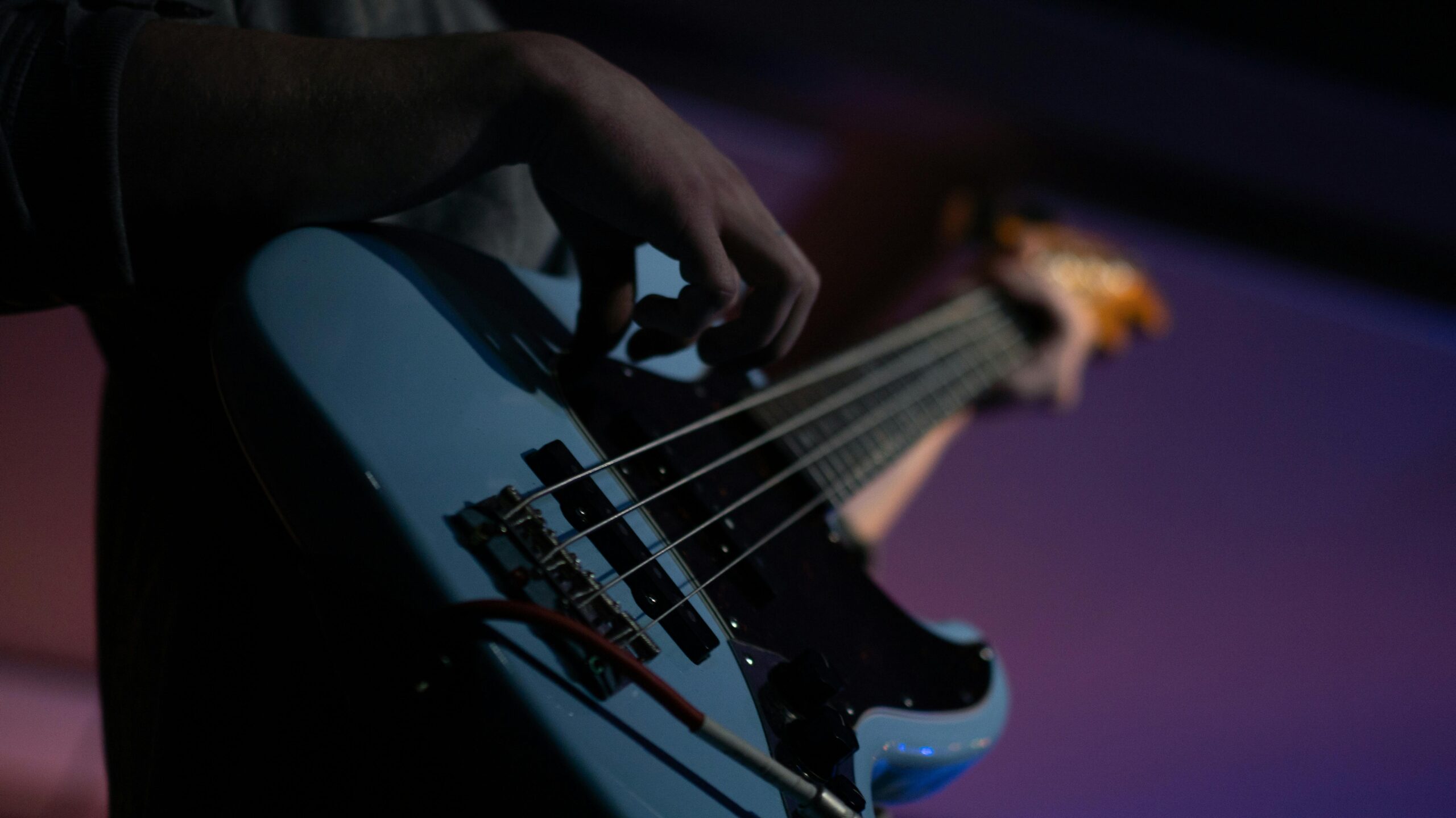 Intimate close-up of a musician playing a bass guitar during a performance.